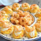 Huevos rellenos decorados con gambas y una pizca de ralladura de huevo. Un aperitivo delicioso y vistoso.