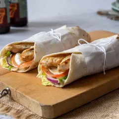 Dos deliciosos wraps de pollo a la parrilla, rellenos de vegetales frescos y queso, listos para disfrutar.