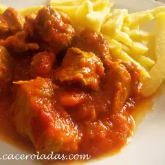 Magro con tomate, jugoso y tierno, servido con patatas fritas crujientes. Un plato casero que reconforta el alma.