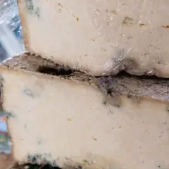 Dos bloques de queso apilados, con moho azul visible, sugieren que es queso en mal estado.