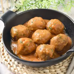 Deliciosas albóndigas caseras en salsa, perfectas para tu próxima receta. Servidas en un cuenco negro con un tenedor al lado.