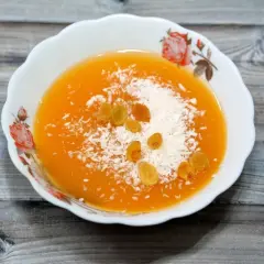 Un postre naranja con coco rallado y pasas, quizás hecho con fécula.