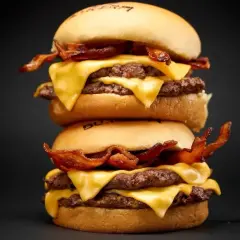 Dos hamburguesas apiladas con queso derretido y tocino crujiente. ¡Una guía visual de como cocinar hamburguesas perfectas!