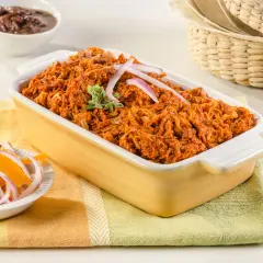 Cochinita pibil, un platillo yucateco de cerdo deshebrado en achiote, servido con cebolla morada y naranja.