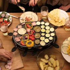 Mesa con raclette, queso, verduras y patatas. ¡Ideas raclette para una cena divertida!