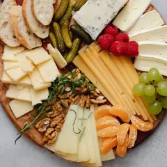 Tabla de quesos como hacerla: variedad de quesos, uvas, frutos rojos, nueces, pepinillos y pan.