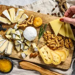 Tabla de quesos variados, incluyendo queso brie con que se acompaña de miel, higos secos, nueces y almendras.