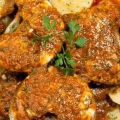 Merluza a la gallega, jugosa y sabrosa, servida con patatas y perejil fresco.