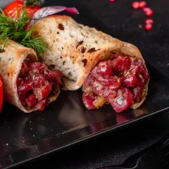 Delicioso steak tartar servido en pan tostado, acompañado de tomates cherry asados y eneldo fresco.