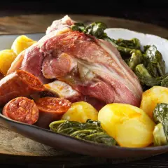 Un plato generoso de lacon con grelos, acompañado de chorizo y patatas cocidas, listo para ser disfrutado.