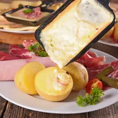 Raclette, comida típica de Suiza, con queso derretido, patatas, embutidos y pepinillos.