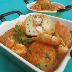 Deliciosas albóndigas de rape con gambas en salsa de tomate, adornadas con perejil fresco.