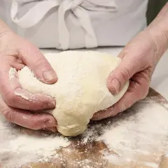 Manos amasando masa con harina, preparando diferentes tipos de levadura para panadería.