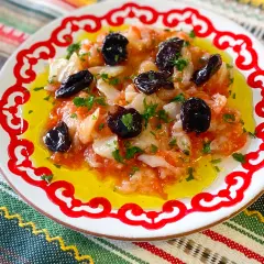 Plato con bacalao desmigado, aceitunas negras y perejil, bañado en aceite de oliva. Una de las muchas recetas de bacalao.