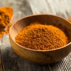 Especias anaranjadas en un cuenco de madera, perfectas para aprender como hacer ras el hanout.