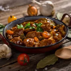 Un delicioso ragú de carne con zanahorias y brócoli en una sartén, acompañado de ajo, cebolla y hierbas.