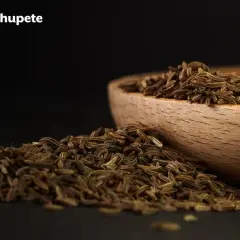 Montón de alcaravea especia cayendo de un cuenco de madera.