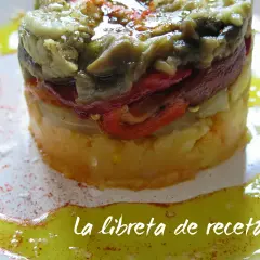 Timbal de escalivada, un plato de verduras asadas en capas, con pimientos rojos y berenjena, servido con aceite de oliva y pimentón.