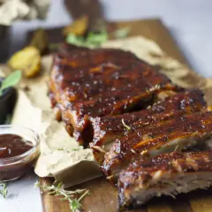 Costillas de cerdo al horno, jugosas y glaseadas, servidas con salsa barbacoa y hierbas frescas. ¡Un festín irresistible!