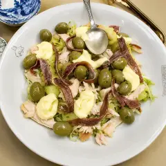 Ensalada fresca con patatas, aceitunas verdes, mayonesa y tiras de anchoas.