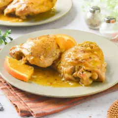 Dos jugosas piezas de pollo a la naranja, bañadas en su salsa y decoradas con gajos de naranja fresca. Un plato delicioso y aromático.