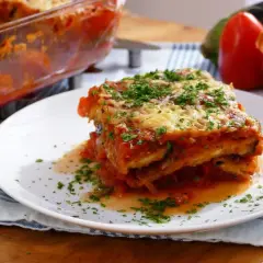 Una porción de parmigiana que es un delicioso plato de berenjenas, salsa de tomate y queso, espolvoreado con perejil fresco.