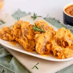 Delicioso lomo en manteca, servido en plato blanco con romero. Un manjar cremoso y apetitoso.