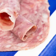 Rodajas de choped enrolladas sobre un plato de rayas azules y blancas.