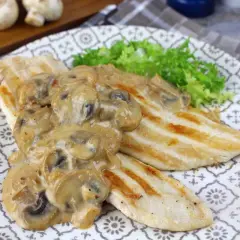 Pechugas de pollo a la parrilla cubiertas con una cremosa salsa de champiñones, servidas con lechuga fresca.