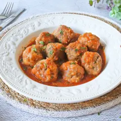 Albóndigas en salsa de la abuela, jugosas y caseras, servidas en un plato blanco con un borde decorado. Un clásico reconfortante.