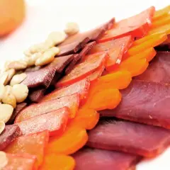 Finas lonchas de carne curada, como la mohama, junto a frutos secos y trozos de fruta deshidratada, crean un plato colorido y apetitoso.