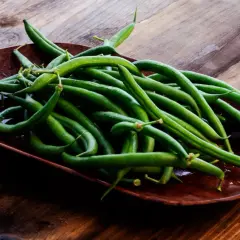 Un plato de judías verdes frescas y vibrantes sobre una mesa de madera rústica, listas para ser cocinadas.