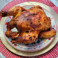 Un jugoso pollo a la brasa, dorado y crujiente, servido en un plato festivo con motivos navideños.