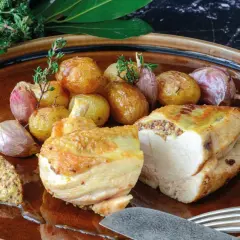 Pollo asado con patatas y ajos, acompañado de una generosa porción de mostaza de grano entero, mostrando varios tipos de mostaza.