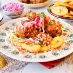 Pollo chuco crujiente con plátanos fritos, pico de gallo y cebolla morada encurtida. ¡Un festín de sabores!