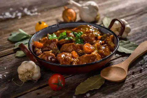 Un delicioso ragú de carne con zanahorias y brócoli en una sartén, acompañado de ajo, cebolla y hierbas.