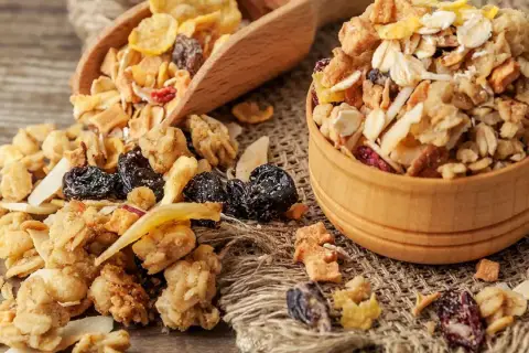 Un tazón de madera lleno de muesli, una mezcla de avena, frutos secos y cereales. El muesli es un desayuno saludable y energético.