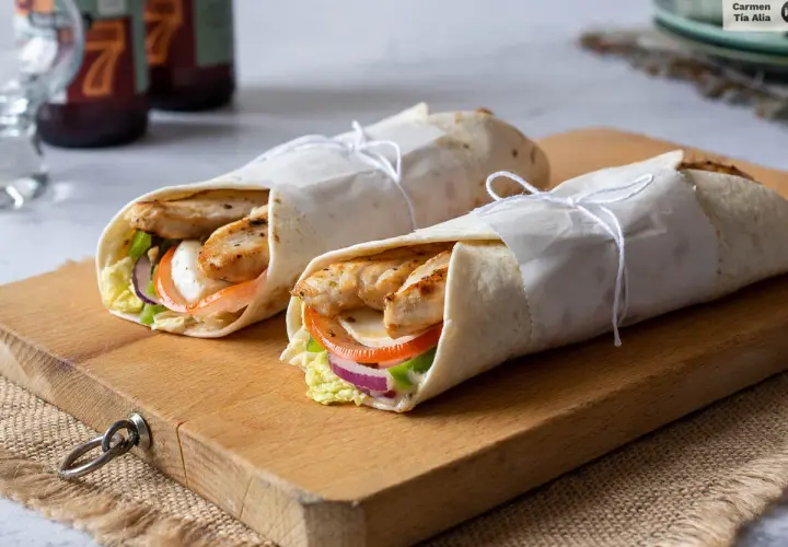 Dos deliciosos wraps de pollo a la parrilla, rellenos de vegetales frescos y queso, listos para disfrutar.