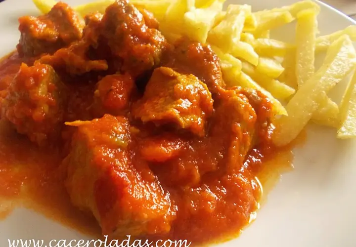 Magro con tomate, jugoso y tierno, servido con patatas fritas crujientes. Un plato casero que reconforta el alma.