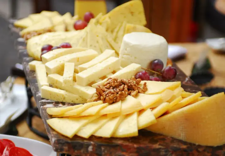 Tabla de quesos variados, cortados en diferentes formas para una presentación ideal. Aprende como cortar quesos para tablas y disfruta de esta delicia.