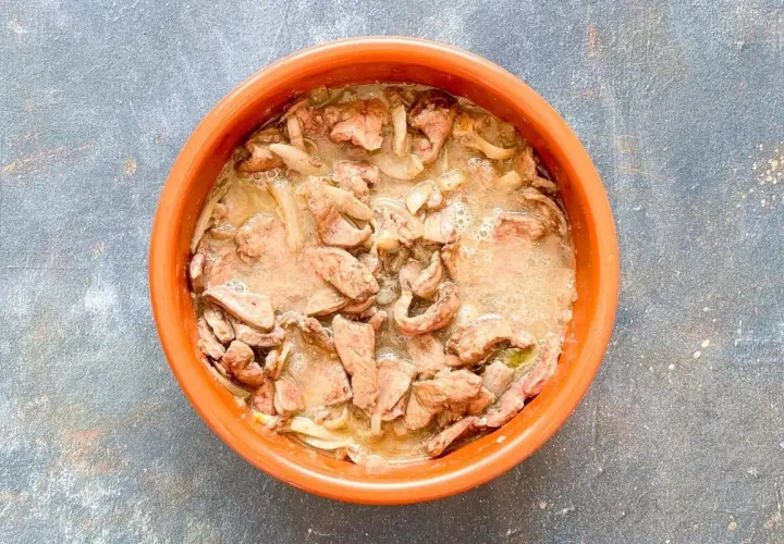 Un plato de barro con un delicioso hígado encebollado, jugoso y lleno de sabor.