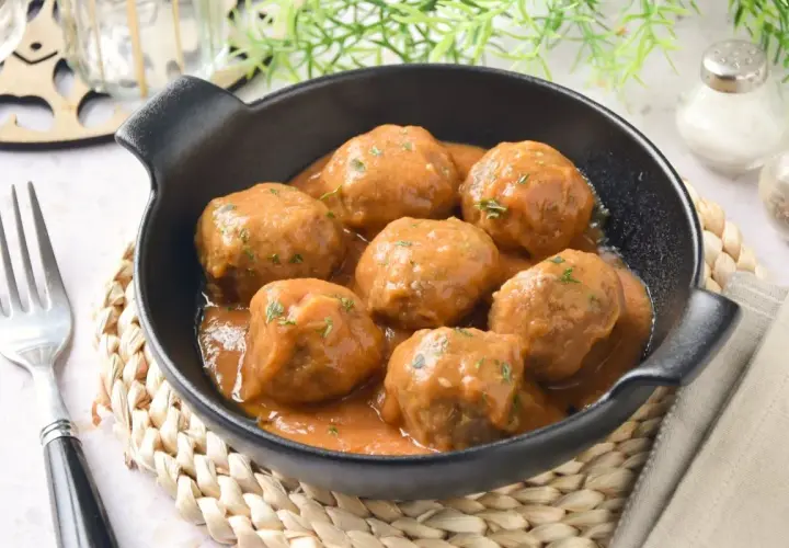 Deliciosas albóndigas caseras en salsa, perfectas para tu próxima receta. Servidas en un cuenco negro con un tenedor al lado.