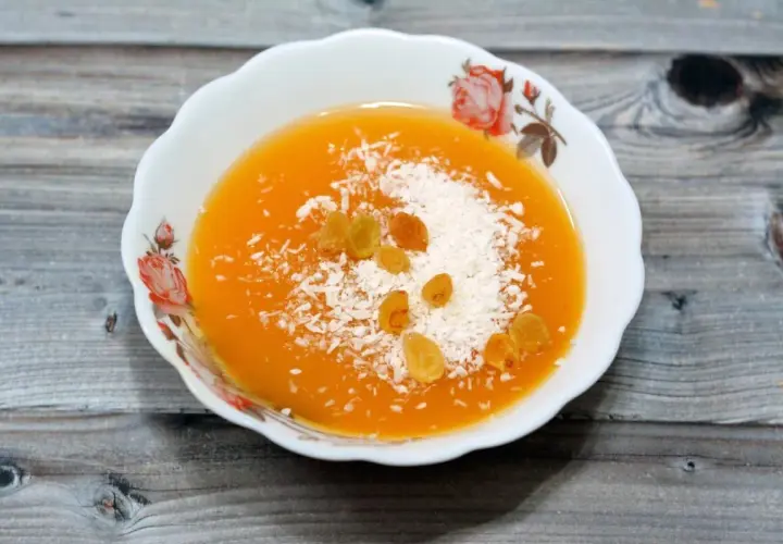Un postre naranja con coco rallado y pasas, quizás hecho con fécula.