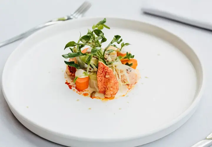 Exquisita ensalada de bogavante gourmet con verduras frescas y una cremosa salsa.