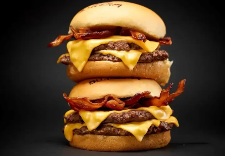Dos hamburguesas apiladas con queso derretido y tocino crujiente. ¡Una guía visual de como cocinar hamburguesas perfectas!