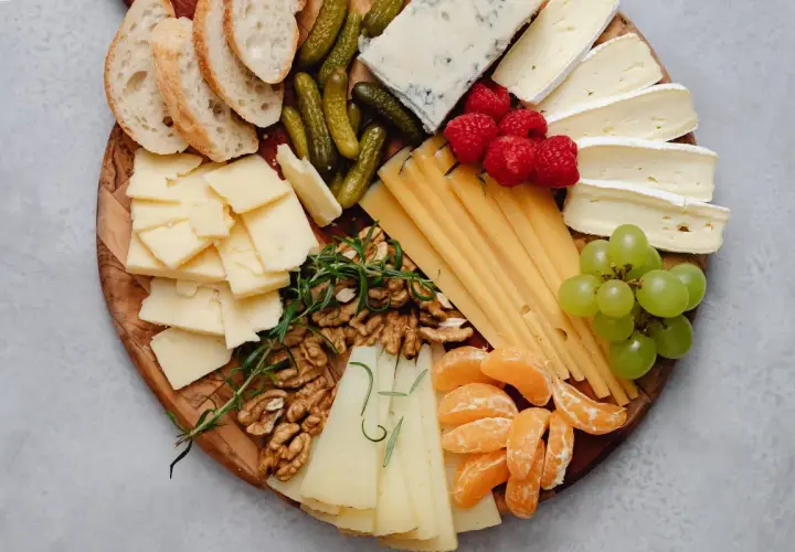 Tabla de quesos como hacerla: variedad de quesos, uvas, frutos rojos, nueces, pepinillos y pan.