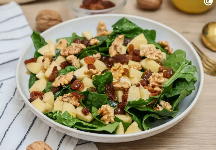 Deliciosa ensalada de espinacas con trozos de manzana, pasas y nueces. Una combinación crujiente y dulce.