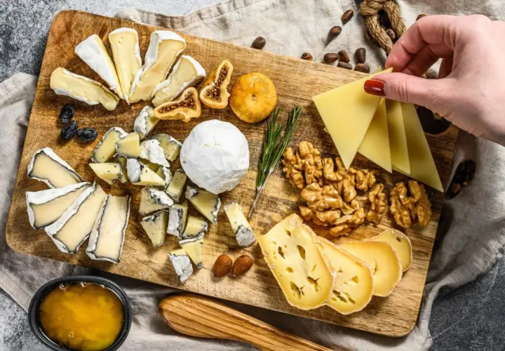 Tabla de quesos variados, incluyendo queso brie con que se acompaña de miel, higos secos, nueces y almendras.