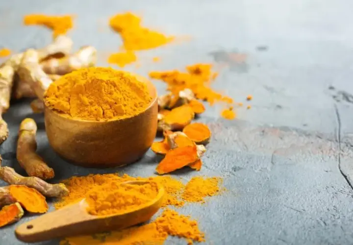 Raíces de cúrcuma y polvo vibrante. La cúrcuma es curry, esencial para dar color y sabor a tus platos.