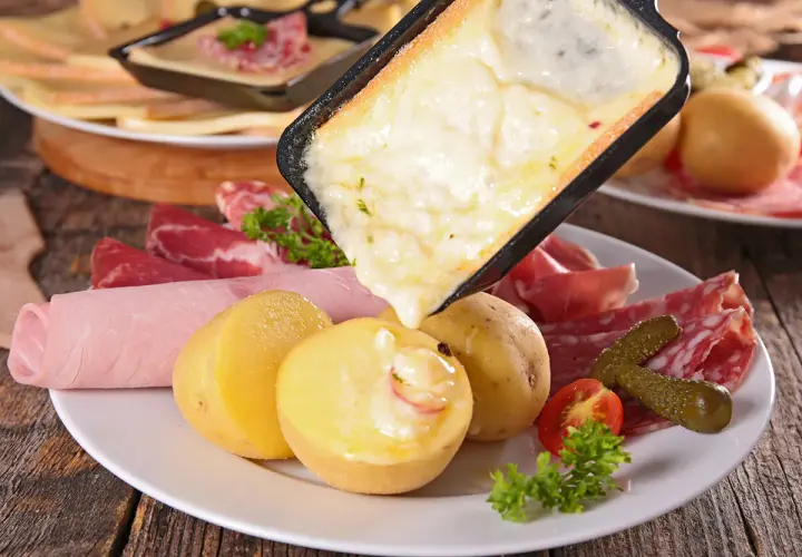 Raclette, comida típica de Suiza, con queso derretido, patatas, embutidos y pepinillos.